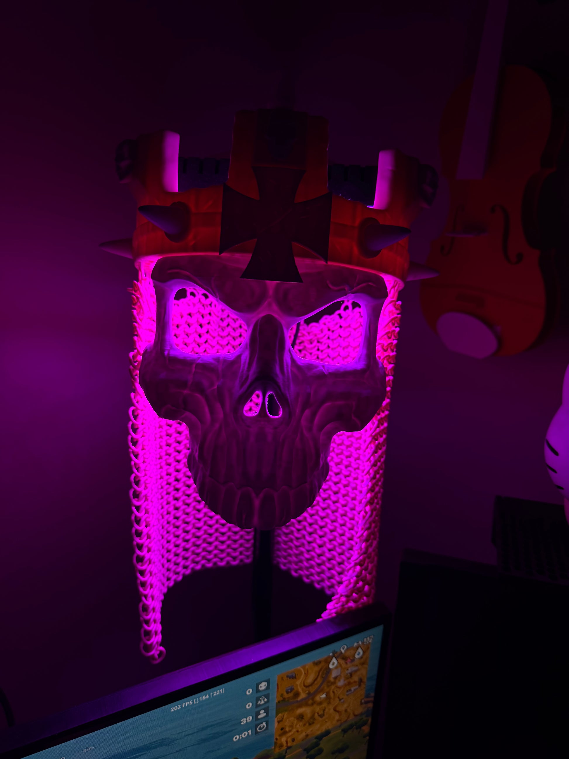 Full front view of the Skull King Crown and skull mask under purple-pink display lighting.