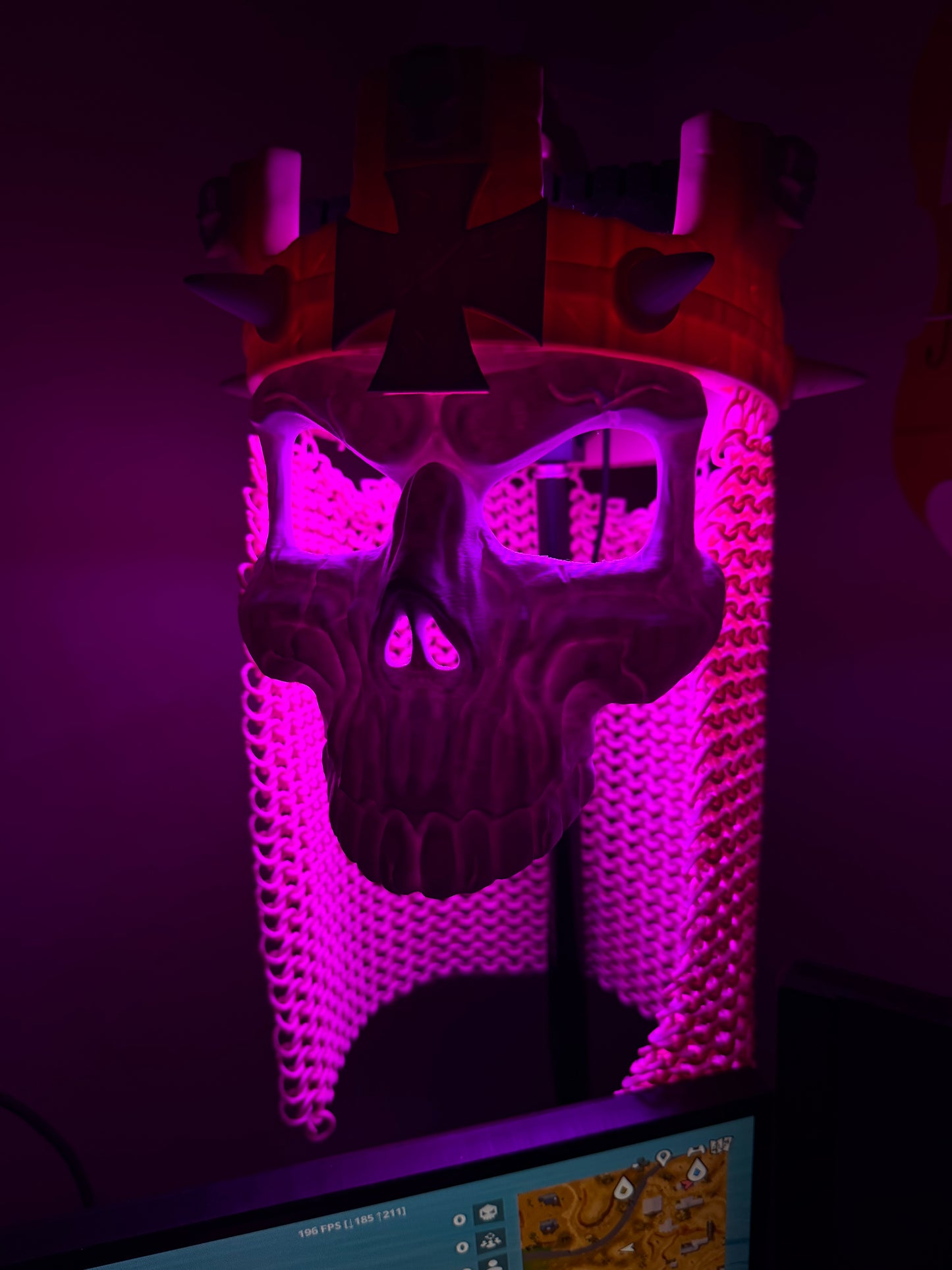 Purple-lit front view of the Skull King Crown and skull mask with illuminated chainmail-style drape.
