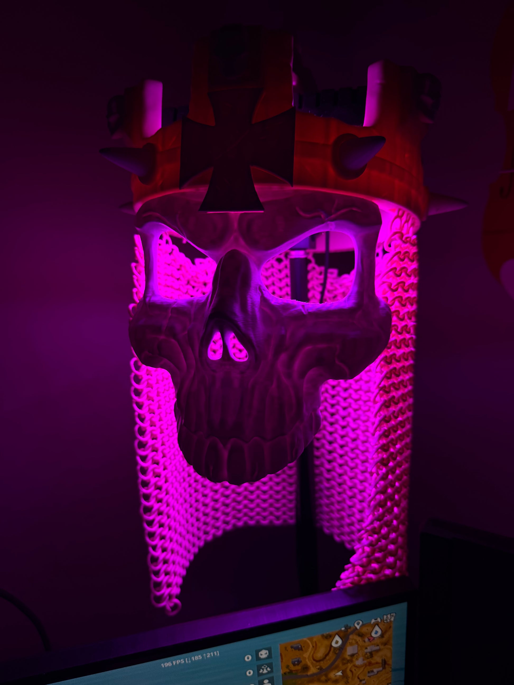 Purple-lit front view of the Skull King Crown and skull mask with illuminated chainmail-style drape.
