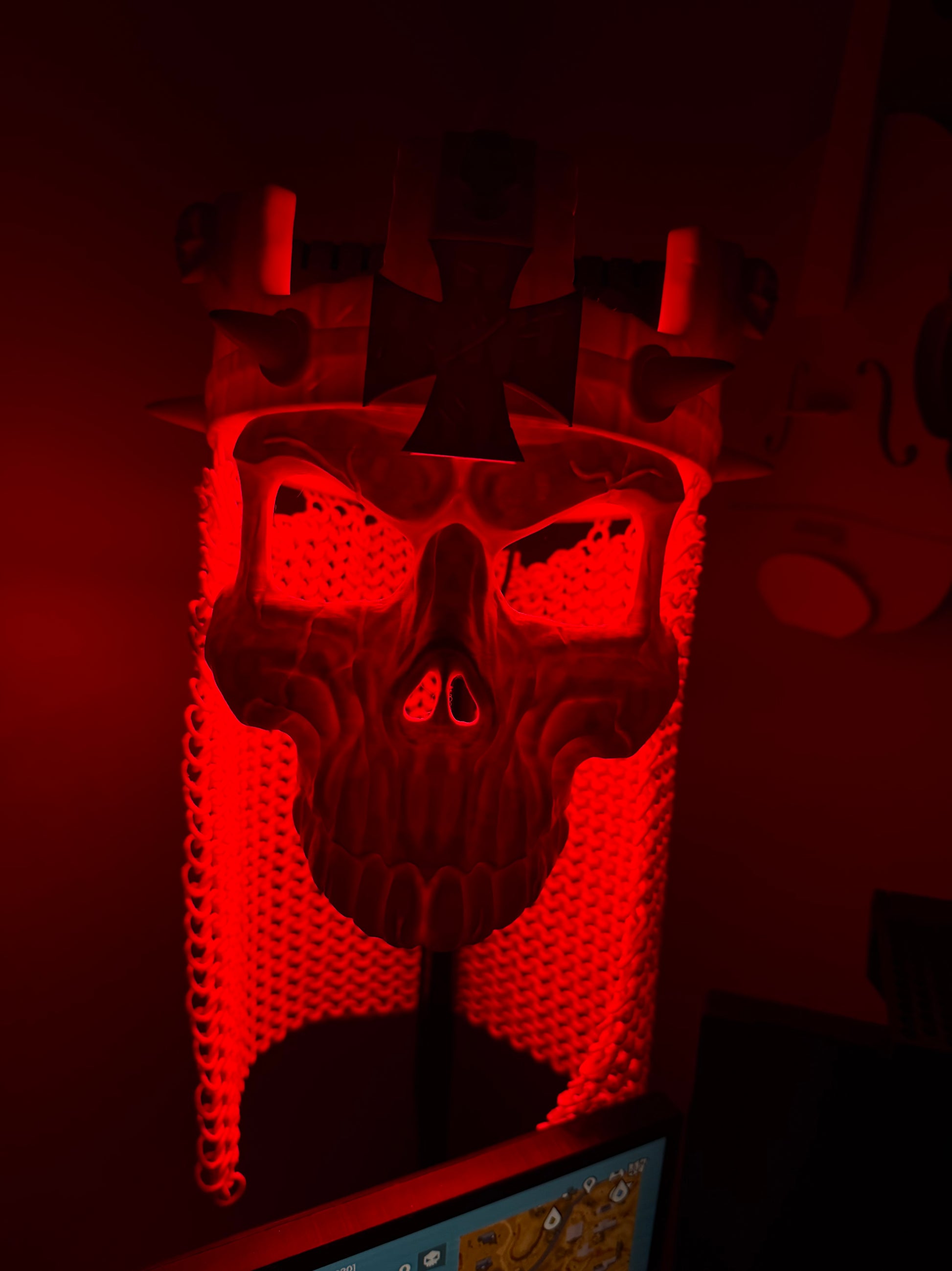 Red-lit close-up of the 3D printed Skull King Crown and skull mask showing the eye openings and crown spikes.