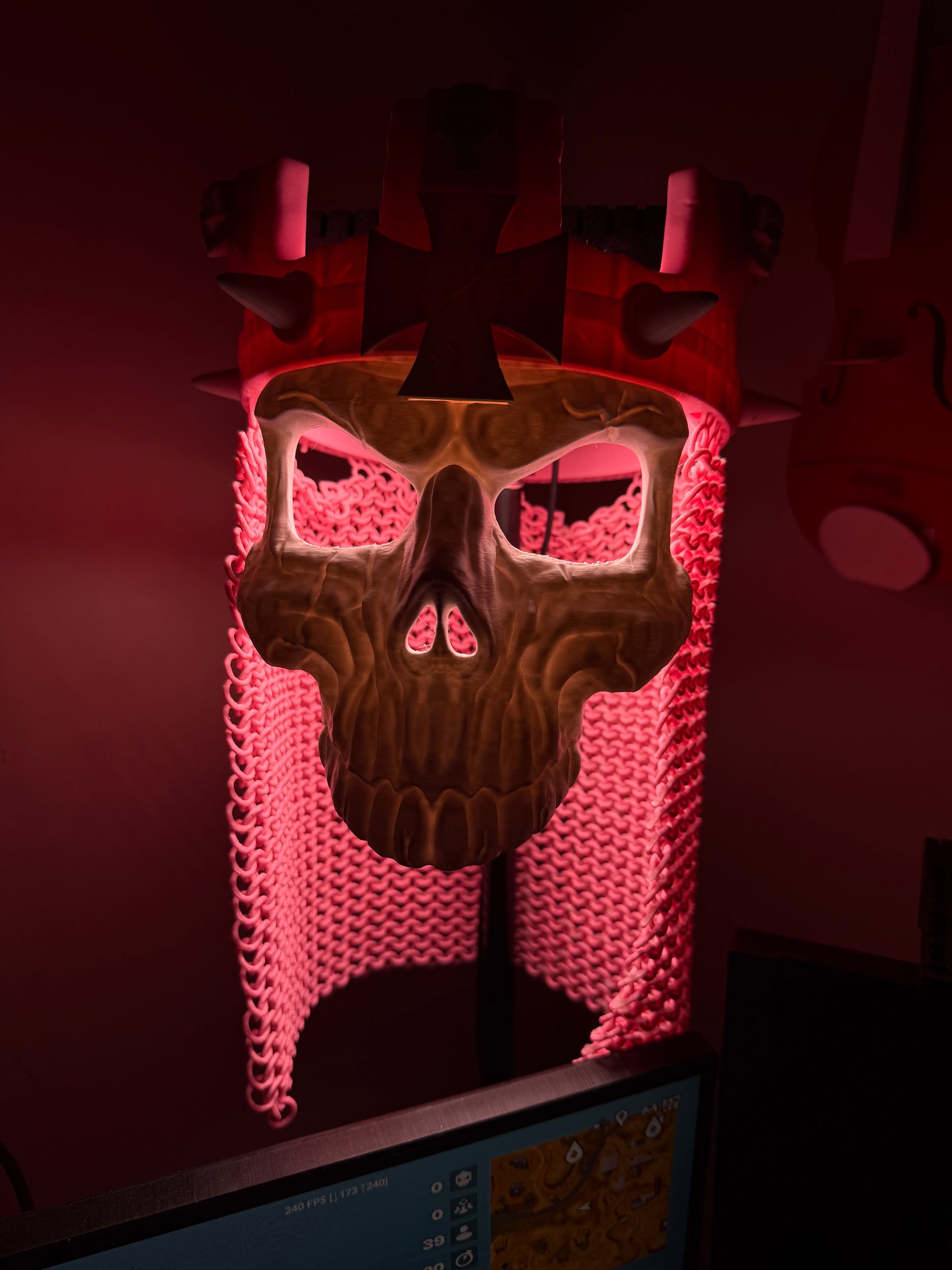 Front close-up of the Skull King Crown and skull mask under pink-red display lighting.